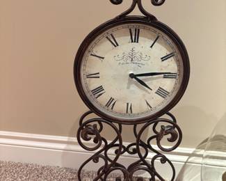 Café des Marguerites Iron Scroll Clock
Charming decorative clock with a distressed dial, Roman numerals, and “Café des Marguerites” motif. Supported by an ornate wrought iron scroll base.
• Condition: Excellent
