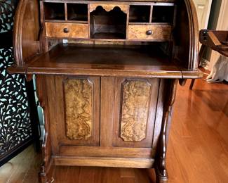 Demure cylinder top desk and antique brass candlesticks.
