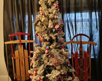 Flocked tree loaded with Santa, snowmen,
and other miscellaneous. Antique sleds.