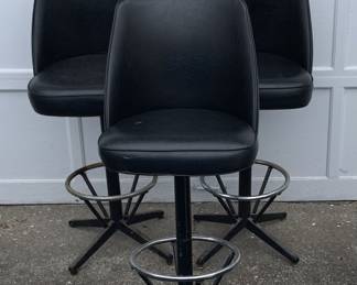 Three black and chrome bar stools covered in vinyl