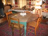 Dining area with primitive drop leaf table, 4 (non-matching) caned seat chairs and room sized oriental rug on floor.