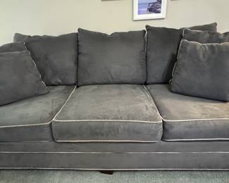 Deep-seated dark gray sofa with cream trim, washable interchangeable cushions, and classic wood club feet.