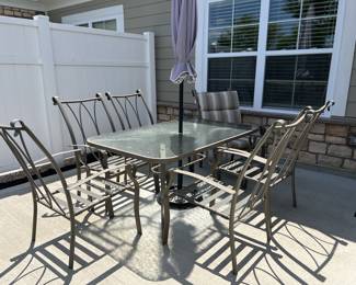 Glass top outdoor table with umbrella, umbrella stand, 6 chairs with cushions.