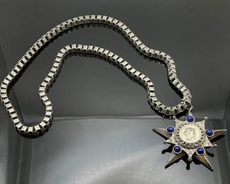 28" silver tone necklace with silver tone 3" star pendant, blue lapis stones surround a coin at the center.