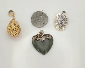 Connemara marble and sterling silver 2" heart pendant from Ireland. Silver tone 1 1/2" sand dollar pendant from Yorkshire. 1 1/2" etched rose pendant and 3" gold tone filigree focal pendant.
