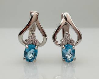 An oval cut 6.7mm x 4.9mm blue topaz with (3) clear cubic zirconias at the top set in sterling silver with a hinge back on each earring. Total weight of topaz stones is approximately 1.56 ctw. 5.8 gtw. Includes certificate provided by consigner.