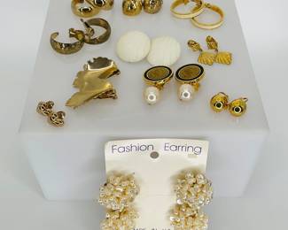 Twelve (12) pairs of fashion clip earrings. All are gold tone or cream colored. All are larger sized, hoops, leaves, hearts and more.