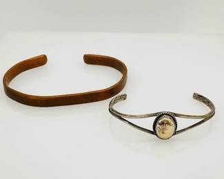 One (1) 6 1/2" copper colored bangle bracelet and (1) 5" sterling silver bangle bracelet with cream colored stone. Stone has a partial design that has rubbed off. 36.32 gtw.