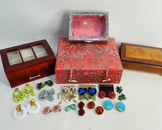 Four vanity top jewelry boxes: (1) with silk exterior, H 3" X W 10" x D 8", (1) wood inlay musical jewelry box that plays "Memory", made in Italy, H 3" x W 8" x D 5", (1) silver with glass top and (1) wood like with glass top and drawer. Also contains an assortment of clip-on earrings. See photos for more details. Shipping-YES