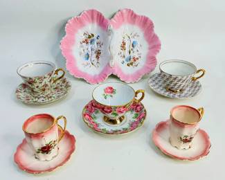 This lot features a KPM porcelain double-sided serving dish, adorned with a crimped and scalloped edge, ornate central handle, and delicate hand-painted floral motif paired with an assortment of fine china teacup and saucer sets.