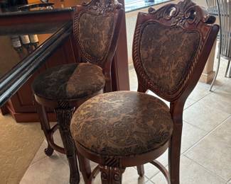 Set of 2 Upholstered Bar Stools – Elegant wood bar stools with carved backs and legs, upholstered in a dark patterned fabric for a refined look. Sturdy and comfortable, perfect for a kitchen island, bar, or entertaining space.