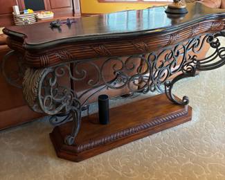 Ambella Console Table – Stunning carved wood and wrought iron console table with black stone inlay top. Features intricate scrollwork and detailed craftsmanship, a hallmark of Ambella design. Perfect for use behind a sofa, in an entryway, or as a statement accent piece. Excellent condition.