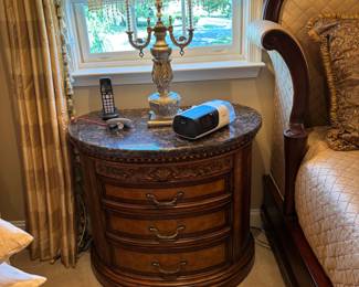 Century Nightstand – A striking round nightstand crafted in rich wood with ornate carved accents and a granite top. Designed with three roomy drawers, each finished with elegant brass-style pulls, this piece offers both beauty and function. Perfect as a bedside companion or as an accent table in a refined traditional setting.