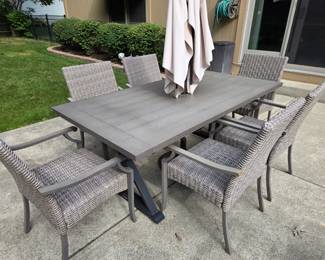 Outdoor wicker patio table, six chairs, and umbrella