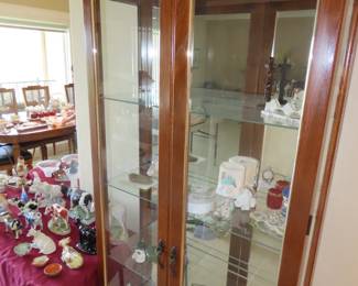 Narrow curio cabinet, glass shelves, mirrored back and lights.