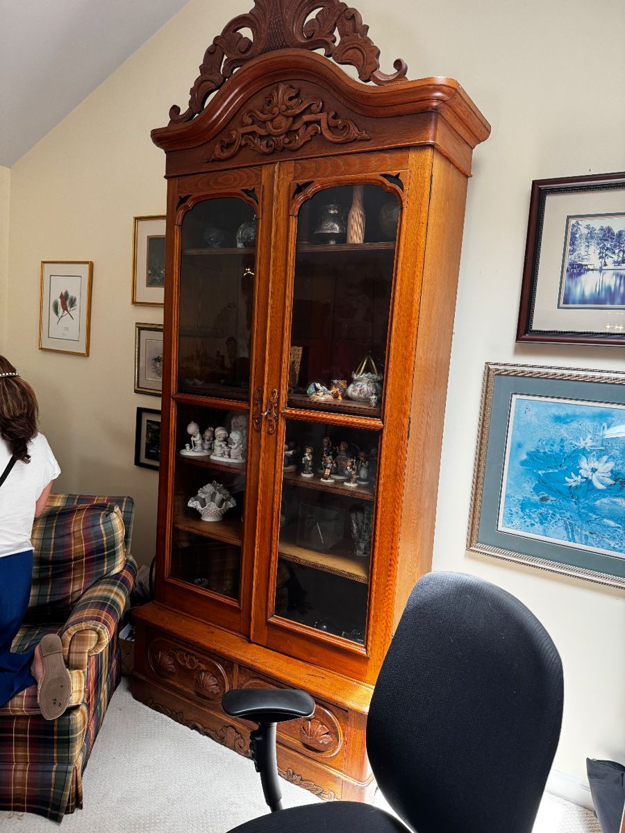Victorian era bookcase, double doors, glass front, drawer below, and elaborate, carved pediment