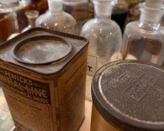 Vintage metal medicine tin "Henrick's" remedy along with large brown glass jar with screw lid and numerous clear apothecary bottles; ideal early pharmacy containers for collectors.