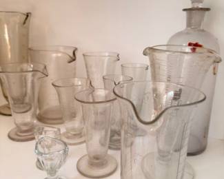 Collection of vintage laboratory glassware including beakers, flasks, and measuring cylinders; antique chemist lab glass
