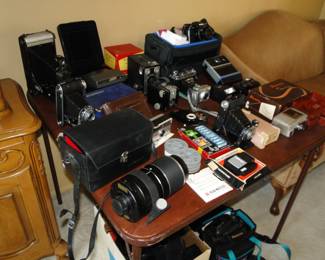 A whole table filled with cameras, and cases