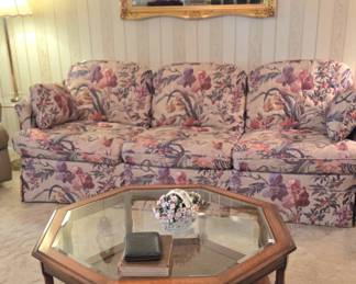 Living room furniture. Octagon glass top coffee table and floral print coach and love seat. Gold ornate mirror 