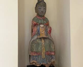 A carved painted wooden Asian figure. 26.5 inches high sitting on a stand that is 10 x 8.