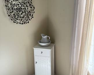 Metal wall art, white cabinet, pitcher and bowl