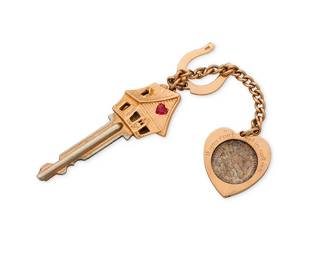 106
Ruser: A 14K Gold House Key
Including a key topped with a gold house element featuring a synthetic ruby heart, accented by a gold horseshoe and dime framed in a heart stating "if you can't get in call me", signed Ruser

Measures: 6 in.
28.9 grams gross
Estimate: $700 - $1,000