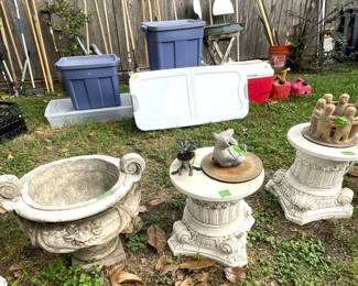 Pair of heavy pedestals and large outdoor urn. Assortment of storage bins and various yard hand tools in background.