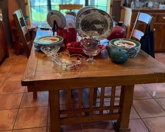 Large wooden kitchen table with four chairs and lots of lovely dishes