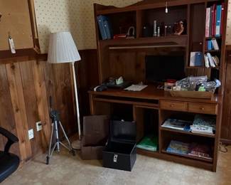 wooden desk with topper, lots of office items and tripod, office chair and large cork board