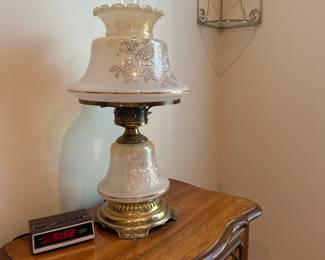Side table, lamps, decor, and vintage alarm clock radio.