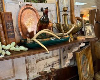 copper trays, antlers, brass candlesticks with gloves, quail planter, old books