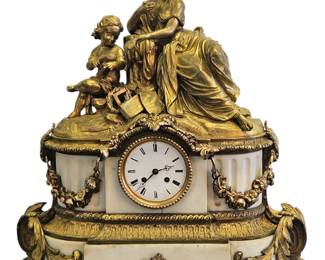 This is an exceptional and rare opportunity to acquire a masterpiece of French horology and sculpture from the Directoire period (c. late 18th Century). This stunning gilt bronze and marble mantle clock is a true work of art, featuring an allegorical scene of a woman, possibly representing Philosophy or Knowledge, seated beside a child. The figures are rendered with exquisite detail and are a testament to the finest craftsmanship of the era. A key feature is the inscribed scroll held by the child, bearing the names of classical thinkers "PLINE," "SENEQUE," and "PLATON," making this a highly unique and intellectually significant piece. The vibrant gilt bronze contrasts beautifully with the elegant white marble base, creating a timeless and sophisticated statement piece that will command attention in any collection.

