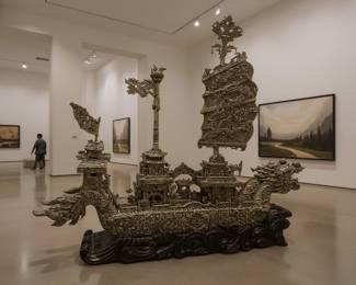 This monumental sculpture is a breathtaking example of traditional Chinese carving, rendered with a level of intricacy and skill that is rarely seen in a material as prized as jade. Meticulously carved from this venerated stone, this lot includes a detailed dragon ship and a separate, removable "shield of arms" that functions as its sail. The shield is a masterpiece in its own right, with a complex, openwork design featuring mythological dragons and symbolic characters. In Chinese culture, jade holds deep symbolic meaning, representing nobility, immortality, and power. This piece is not just a sculpture; it is a celebration of Chinese mythology and naval history, and its size and complexity make it an incredible centerpiece for any collection of Asian art.
