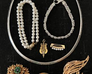 Fine jewelry, including (bottom row left to right) an 18K gold flower pin with small sapphires and green enameled flowers; a 14K gold circle pin w/floral motif featuring four small birthstones; and a 14K gold pin with nine cultured pearls.