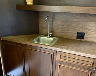 The sunken bar area, including walnut cabinets, bifold doors, vintage stainless steel sink