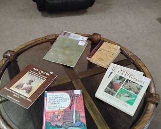 Glass top round coffee table with brass accents and rattan storage shelf beneath it.