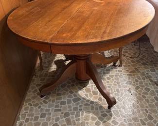 Oak table with pedestal base has wheels and 4 chairs