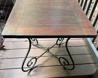 Vintage Wood & Wrought Iron Side Table - $40
Charming vintage square side table with a rich wood top and decorative wrought iron scroll base accented with a brass finial. The piece has a warm, rustic character with some age-appropriate wear on the top (light scratches and marks shown in photos), giving it an authentic vintage patina.
	•	Square wood top with natural wear and character
	•	Decorative wrought iron scroll legs with cross-brace
	•	Brass center finial accent
	•	Solid and sturdy

Approx. dimensions: 24” W x 24” D x 23” H

