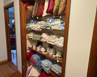 Hall area shelving loaded with linens, throw pillows, etc.