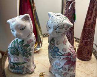 Pair of decorative kitties with art glass in the background.