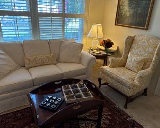 Another view of the 3-cushion ivory couch, and wing-back chair, round hand-painted vintage table, with Waterford lamp, acrylic landscape painting, wool area rug and more!