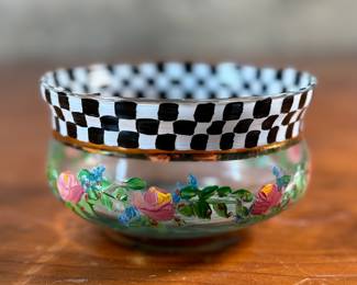 This lot features a vintage hand painted bowl by Victoria & Richard Mackenzie-Childs. Maker mark underneath as shown in photos. The MacKenzie-Childs story began with Victoria and Richard MacKenzie-Childs in 1983, creating hand-painted ceramics in rural New York, a style later called “tradition with a twist” and inspired by the couple’s daughter. After facing bankruptcy in 2000 due to financial issues, the brand was acquired in 2001 by Pleasant Rowland, founder of the American Girl doll company. Despite a subsequent dispute and the founders’ departure, MacKenzie-Childs is now a thriving luxury home decor company known for its signature Courtly Check pattern and other whimsical, handcrafted designs.  
