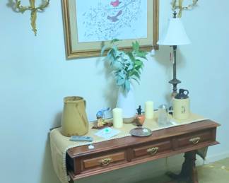 Sofa table with drawers.  Holding pottery jugs, above are two beautiful candle sconces and a gorgeous picture with birds, signed.