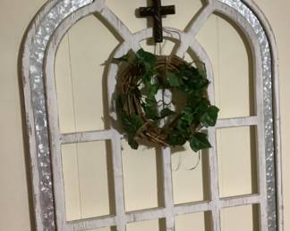A wood and metal window with grape wreath and cross.