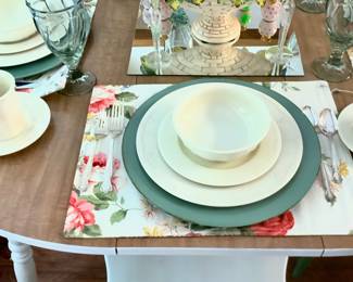 The table setting on the breakfast table.  Has white China with beautiful colorful place mats. 
