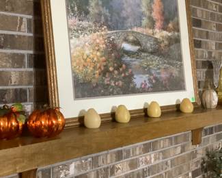 A piece of beautiful framed art with the pumpkins and candles.