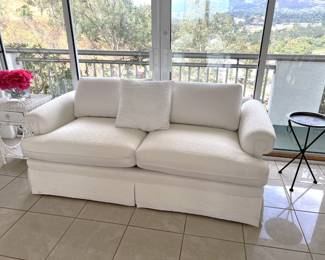 Here is a wonderful, white loveseat sofa, along with a side table with a small drawer (under the red flowers).