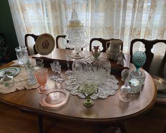 Dining room table with two leaves and six chairs.  And resting on it is beautiful glassware..