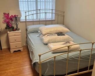 full size bed, small bedside table, pillows, lamp and floral decor